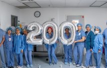 STHS Heart Robotic surgery team holding balloons that spell out '200'.